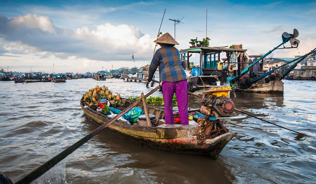 A woman sails a boat to sell fruits in the Cai Rang floating market
